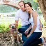 Couple sitting together with their brown puppy